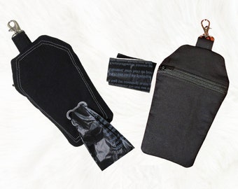 May include: Two black fabric dog poop bag holders shaped like coffins. One has a zipper closure and the other has a flap with a snap closure. Both have a silver clip for attaching to a leash.