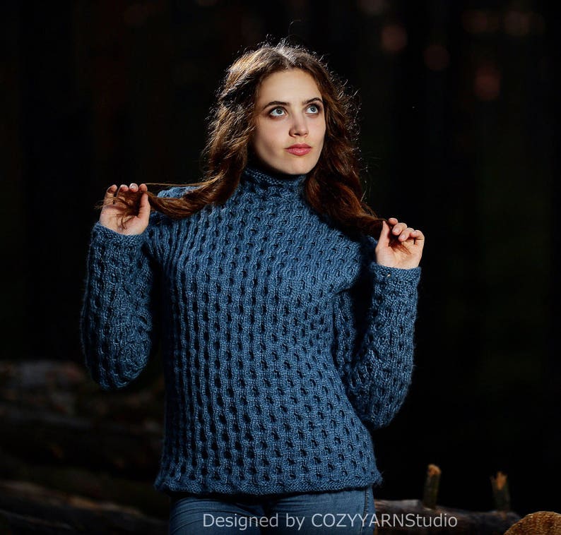 May include: A blue knitted sweater with a textured pattern. The sweater has a high neck and long sleeves.