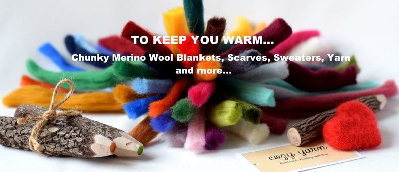 May include: A colorful assortment of chunky merino wool yarn in various shades, including red, blue, green, yellow, and purple. The yarn is arranged in a circular shape, with a wooden log and a pencil in the foreground. The text "TO KEEP YOU WARM... Chunky Merino Wool Blankets, Scarves, Sweaters, Yarn and more..." is displayed above the yarn. The text "cozy yarn" is displayed below the yarn.