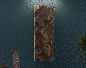 May include: A wooden wall art piece with a natural wood grain pattern hangs on a teal blue wall with a leafy pattern. A potted plant sits on the floor next to the wall art.