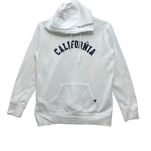 May include: White hooded sweatshirt with a navy blue "CALIFORNIA" graphic on the front and "QUIKSILVER" text on the hood.