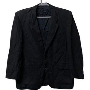 May include: A black blazer hanging on a gray hanger. The blazer has a notched lapel, two front pockets, and a two-button closure. The fabric appears to be a textured material.
