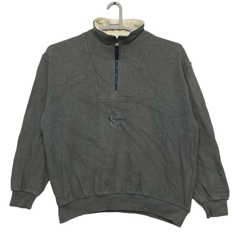 May include: A gray half-zip sweatshirt with a white fleece lining. The sweatshirt has a small embroidered logo on the front that says "G-Shock".