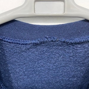 May include: A navy blue sweatshirt with a ribbed neckline.