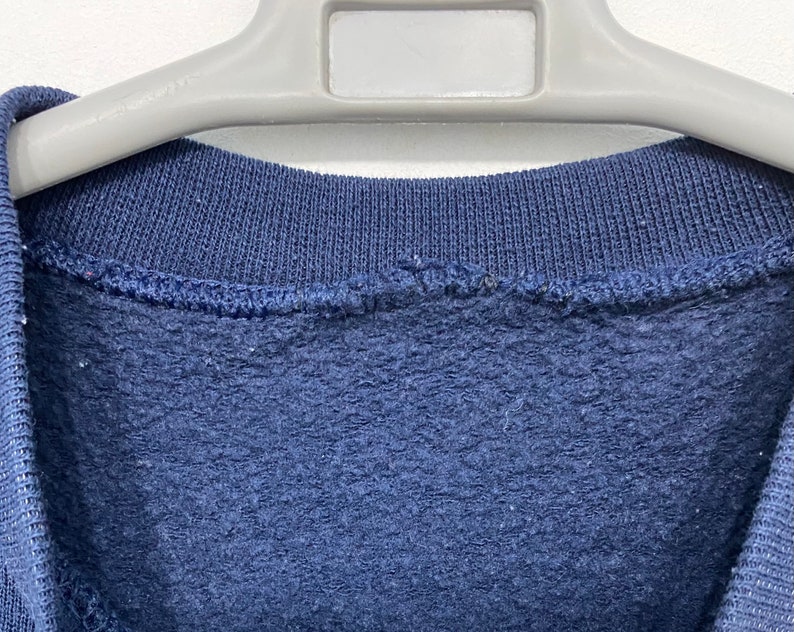 May include: A navy blue sweatshirt with a ribbed neckline.