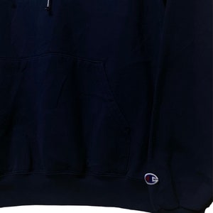 May include: A navy blue hooded sweatshirt with a blue and white North Carolina Tar Heels logo on the front and a Champion logo on the left sleeve.