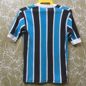 May include: A striped short-sleeved shirt with blue and black vertical stripes. The shirt has a white collar and cuffs.