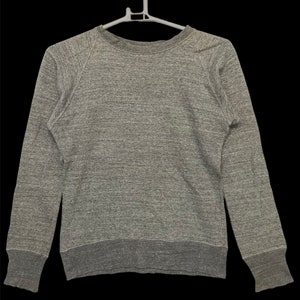 Könnte beinhalten: Ein grauer Melange-Sweatshirt mit langen Ärmeln und einem Rundhalsausschnitt.
