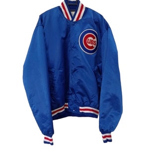 May include: A blue satin baseball jacket with red and white striped ribbing around the collar, cuffs, and waist. The jacket has a button closure and features a large embroidered Chicago Cubs logo on the left chest.