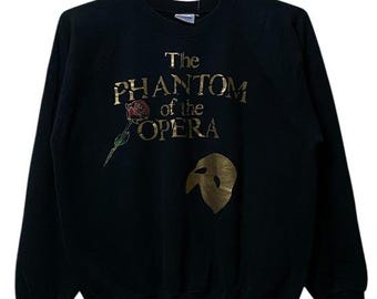 May include: Black sweatshirt with a gold print of "The Phantom of the Opera" with a rose and a mask.