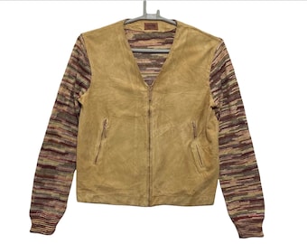 Puede incluir: Una chaqueta de ante marrón con cierre de cremallera y un patrón de punto multicolor en las mangas.