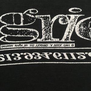May include: Black t-shirt with a distressed white graphic. The graphic features the word "ERIC" in a stylized font above a line of text. The text includes the year 1993 and the phrase "all rights reserved."