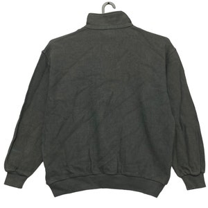 May include: A dark gray, long-sleeved sweatshirt with a mock neck and a zipper closure. The sweatshirt has a relaxed fit and is made of a soft, comfortable fabric.