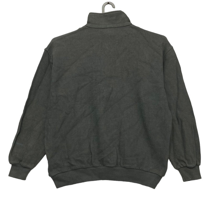 May include: A dark gray, long-sleeved sweatshirt with a mock neck and a zipper closure. The sweatshirt has a relaxed fit and is made of a soft, comfortable fabric.