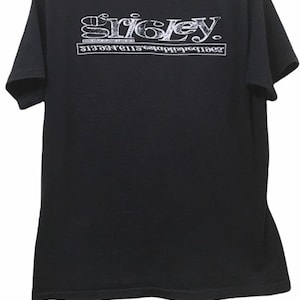 May include: Black t-shirt with white text. The text on the shirt reads "Sricley" above a second line of text. The shirt is made of a soft material and has short sleeves.