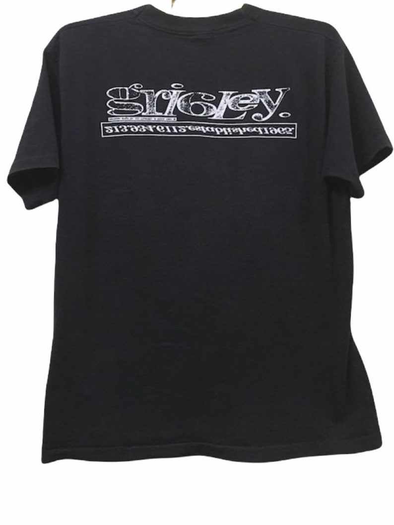 May include: Black t-shirt with white text. The text on the shirt reads "Sricley" above a second line of text. The shirt is made of a soft material and has short sleeves.