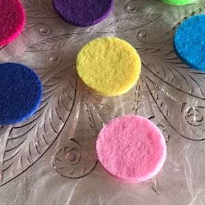Peut inclure: Assortiment de cercles en feutre de diff&eacute;rentes couleurs, rose, bleu, jaune, violet et bleu clair, dispos&eacute;s sur une surface blanche textur&eacute;e.