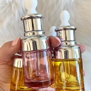 Puede incluir: Tres botellas de vidrio con gotero, con tapas plateadas y goteros blancos. Las botellas est&aacute;n llenas de l&iacute;quidos rosa y amarillo.