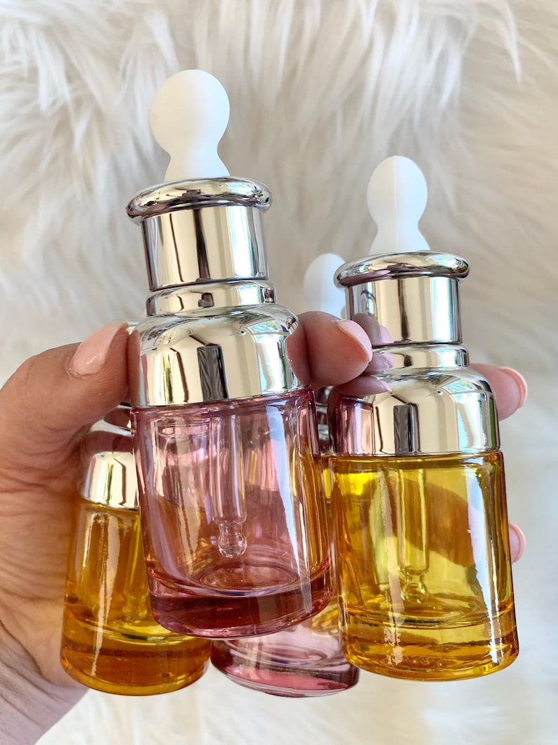 Puede incluir: Tres botellas de vidrio con gotero, con tapas plateadas y goteros blancos. Las botellas est&aacute;n llenas de l&iacute;quidos rosa y amarillo.