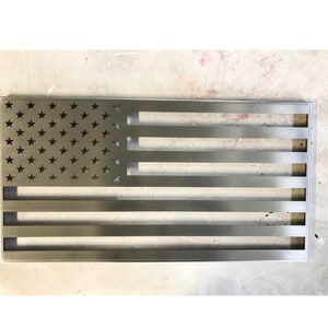 May include: A metal American flag with a distressed finish. The stars are cut out of the metal, and the stripes are raised.