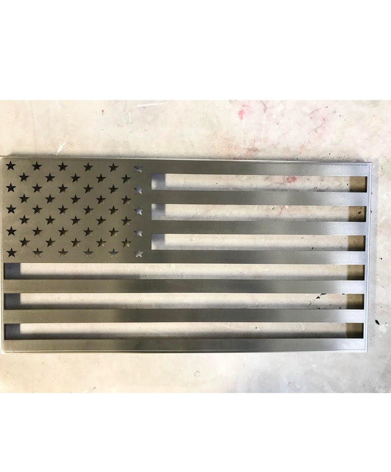 May include: A metal American flag with a distressed finish. The stars are cut out of the metal, and the stripes are raised.