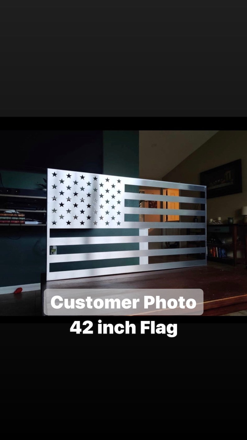 May include: A silver metal American flag wall decor with a 42 inch size. The flag is mounted on a wooden surface.