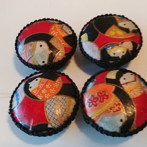 May include: Four round decorative cabinet knobs. Each knob features a colorful Japanese-style design with red, black, and white elements. The edges are trimmed with a black, braided trim.