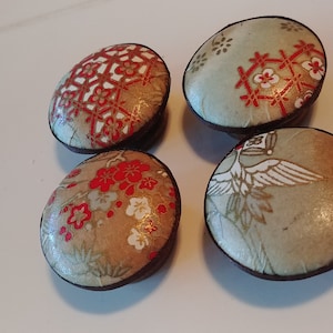 May include: Four decorative cabinet knobs with a Japanese-inspired design. Each knob features a different pattern, including red and white floral motifs, geometric shapes, and a bird. The knobs have a brown base and a light-colored top.