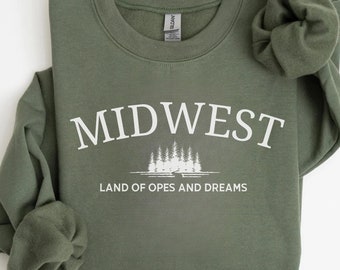 May include: A green sweatshirt with the text "MIDWEST LAND OF OPES AND DREAMS" in white lettering. The sweatshirt has a white graphic of trees and a lake.