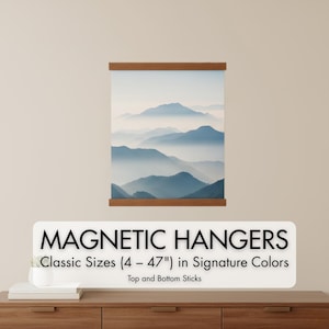 May include: A framed print of a mountain landscape in shades of blue and white, held by wooden magnetic hangers. The text "MAGNETIC HANGERS" is displayed below the print, with size details ranging from 4 to 47 inches.