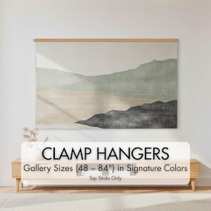 Puede incluir: Una impresión artística de paisaje con un diseño de montaña en tonos verdes, beige y negro, exhibida con un colgador de pinza de madera. El texto en la imagen dice "CLAMP HANGERS Gallery Sizes (122 - 213 cm) in Signature Colors Top Sticks Only."