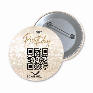 May include: A round button with a gold glitter background and the text "It's My Birthday" in gold script. A black and white QR code is in the center with the text "Scan Me" below it.
