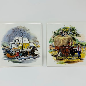 May include: Two vintage ceramic tiles with winter and summer scenes. The first tile depicts a horse-drawn sleigh with a couple inside, traveling through a snowy landscape with a yellow house in the background. The second tile shows a hay bale with children playing on top, two oxen pulling a cart, and a dog running in the foreground.