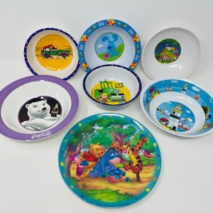 May include: Set of eight colorful plastic bowls with various cartoon characters, including Winnie the Pooh, Tigger, Eeyore, and a polar bear drinking Coca-Cola.