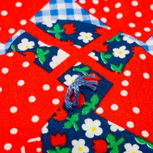 May include: Close-up of a blue and white fabric with a floral pattern. The fabric is sewn together with a blue thread.