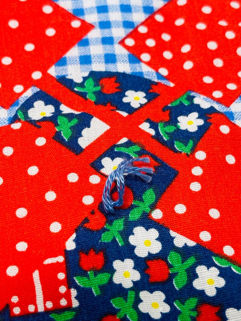 May include: Close-up of a blue and white fabric with a floral pattern. The fabric is sewn together with a blue thread.