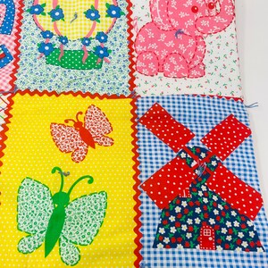 May include: A colorful patchwork quilt with a hot air balloon, elephant, butterfly, and windmill design. The quilt is made of different fabrics with various patterns, including gingham, polka dots, and floral prints.