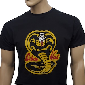 May include: Black t-shirt with a yellow cobra graphic and the text "Cobra Kai" in red and yellow lettering.