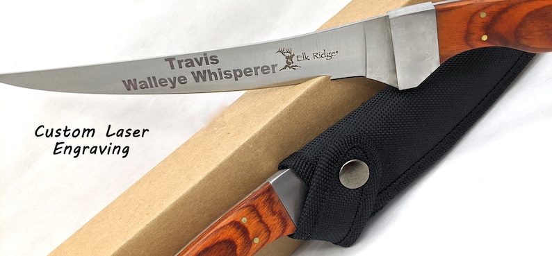 Puede incluir: Un cuchillo de pesca de acero inoxidable personalizado con mango de madera y funda de nylon negra. La hoja est&aacute; grabada con "Travis Walleye Whisperer Elk Ridge".