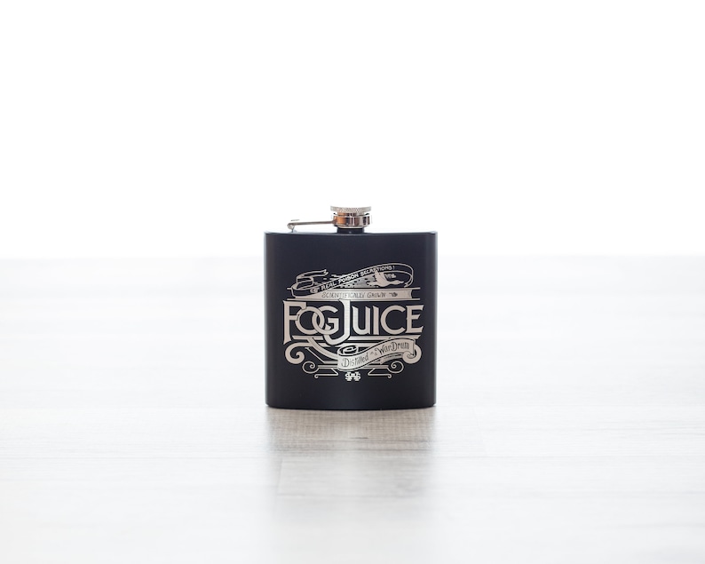 K&ouml;nnte beinhalten: Schwarze Metallflasche mit silbernem Deckel und silbernem Design, auf dem "Fog Juice" und "Distilled in Your Dream" steht.