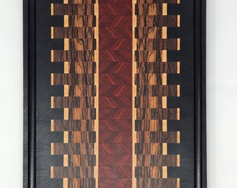 Könnte beinhalten: Ein Schneidebrett aus Holz mit schwarzem Rahmen und einem rot-braun-schwarzen Schachbrettmuster.