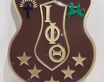 May include: A brown shield-shaped plaque with gold trim and five gold stars. The plaque features a gold Greek letter design with the letters "I", "Φ", and "Ο" in a circle. The plaque also features a black cross with a sunburst design, a red candle in a lamp, and a green centaur.