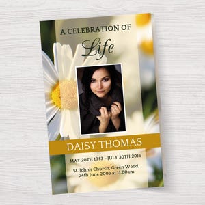 Könnte beinhalten: Eine weiße Margerite mit gelber Mitte ist auf einer Trauerkarte abgebildet. Die Karte hat einen goldenen Rand und den Text "A Celebration of Life" und "Daisy Thomas" in Schwarz. Die Karte enthält auch die Daten "May 20th 1943 - July 30th 2016" und "24th June 2003 at 11.00am". Ein Foto einer Frau mit dunklen Haaren befindet sich in der Mitte der Karte.