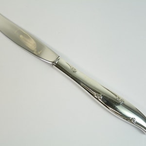 Könnte beinhalten: Ein silbernes Dinnermesser mit einem floralen Muster auf dem Griff.