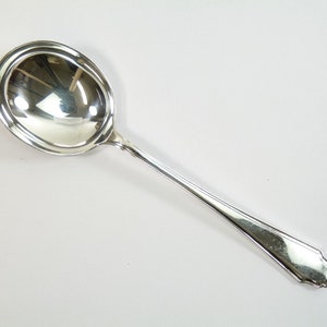 May include: A silver soup spoon with a rounded bowl and a simple, elegant handle.