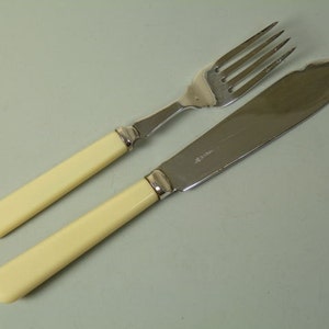 May include: A set of silver cutlery with ivory handles. The fork and knife are laid out side by side.