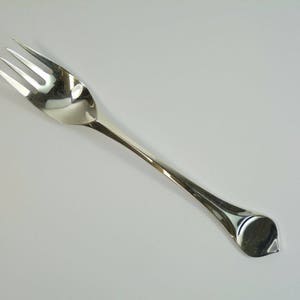May include: A silver fork with a pointed handle. The fork has three prongs and a polished finish.