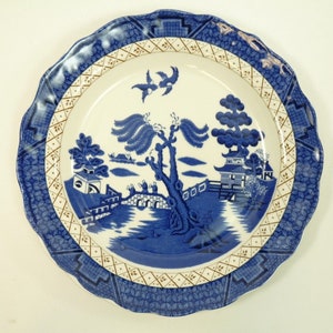 Op de afbeelding: Een blauw en wit porseleinen dinerbord met een traditioneel wilgenmotief. Het bord heeft een gegolfde rand en een gouden rand.
