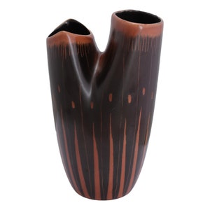 Könnte beinhalten: Eine braune und schwarze Keramikvase mit einem einzigartigen, abstrakten Design. Die Vase hat eine hohe, schlanke Form mit zwei Öffnungen an der Oberseite.