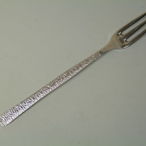 Może przedstawiać: Srebrny widelec z teksturowanym uchwytem. Widelec ma około 19 cm długości.